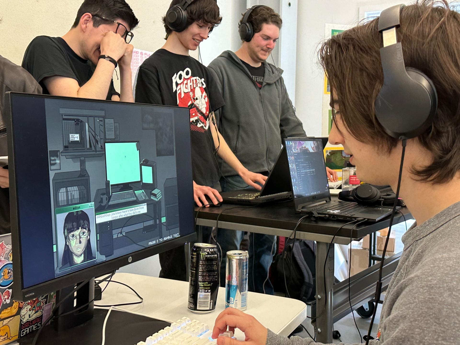 4 students playing a game at the UCSC games showcase. The student closest to the front has on headphones